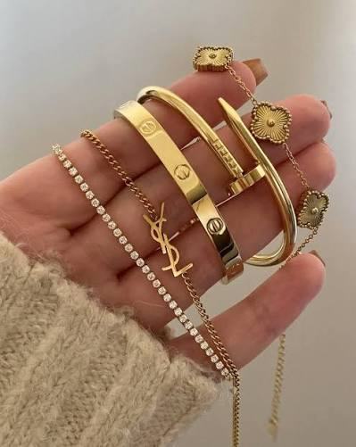 Hand wearing Cartier, YSL and Van Cleef designer gold bracelets